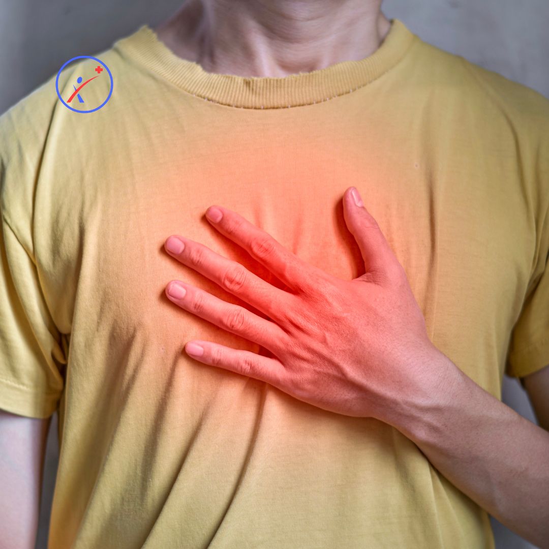 Oseba v rumeni majici se s svojo levo roko drži za osrednji del prsnega koša. Shematsko je prikazana bolečina v osrednjem delu prsnega koša.